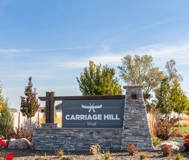 Stone and timber entrance monument sign reading Carriage Hill West in Nampa, Idaho