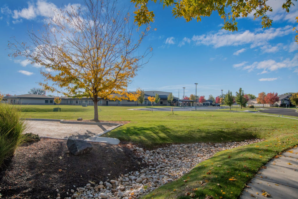 Neighborhood park with mature trees, a paved walking path and open green space in a south Nampa, Idaho community